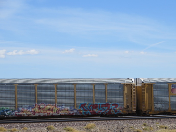Colorful tagged cattle cars rolling East